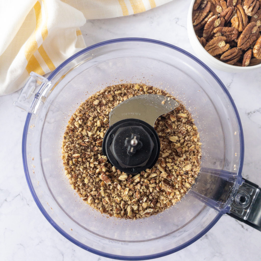 Chopped pecans in bowl of food processor 