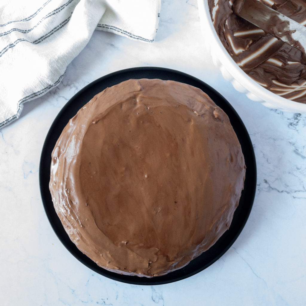 cake iced with chocolate icing with empty bowl in top right corner