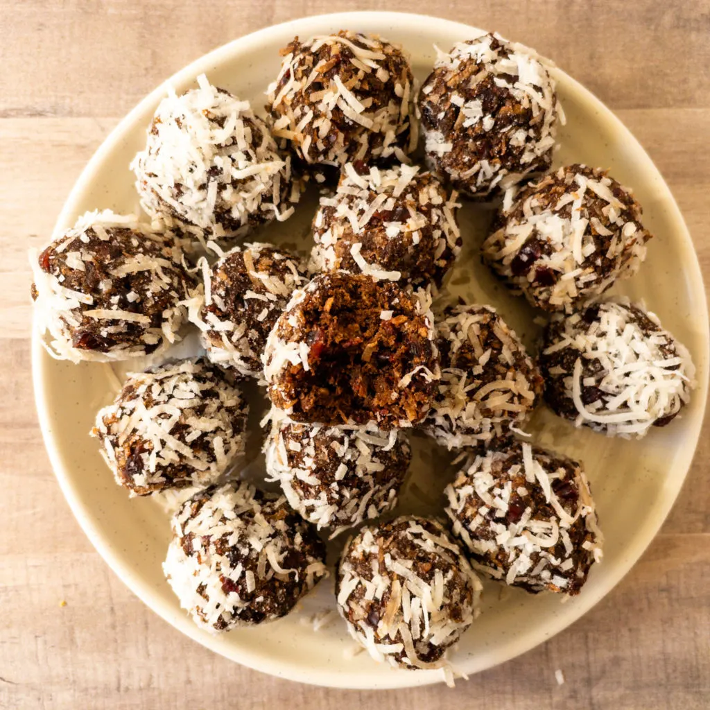 Cranberry cocoa bliss balls in a pile with bite missing from top ball