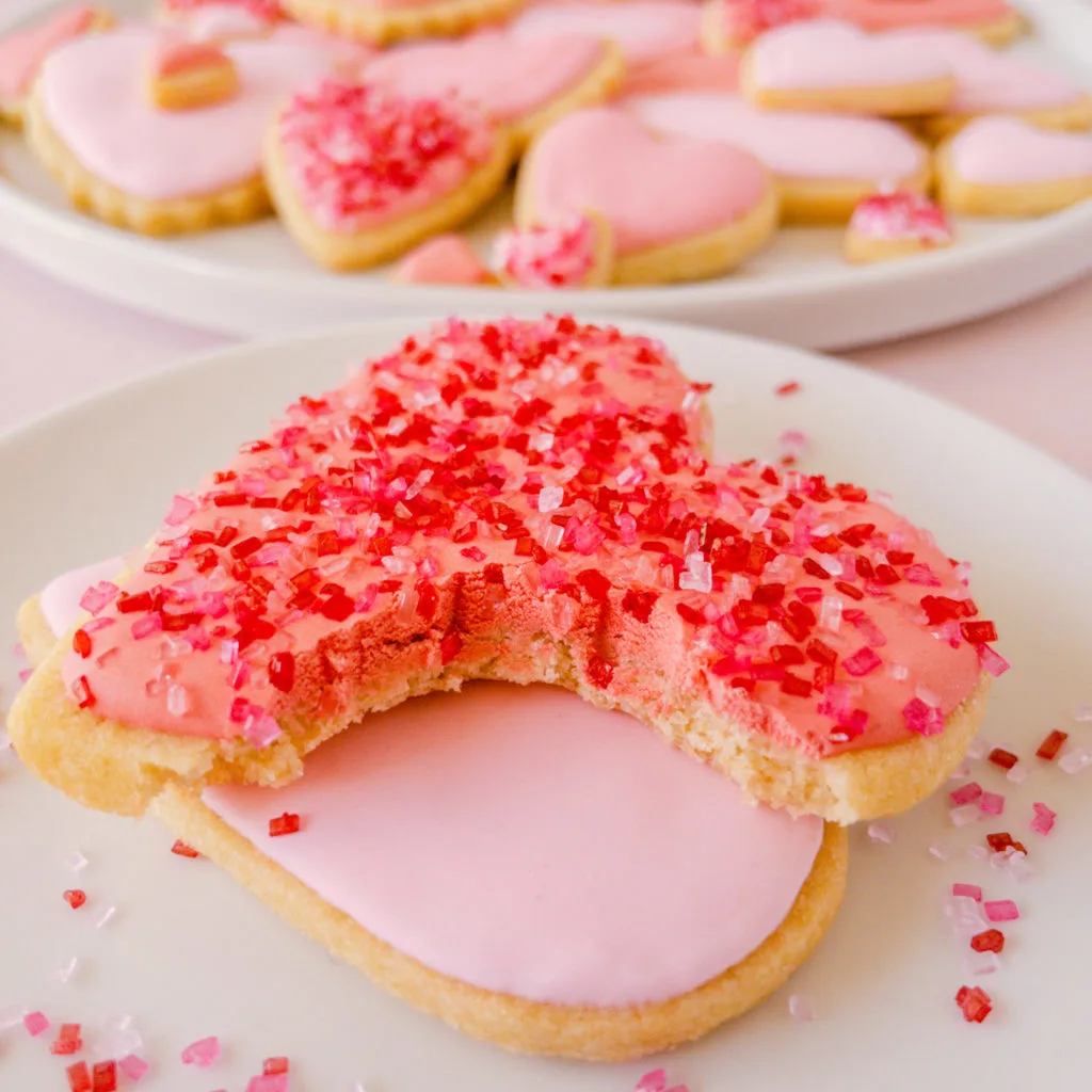 two heart shaped sugar cookies stacked with bite missing from top cookie