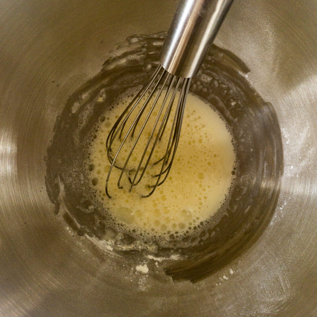 Meringue powder, corn syrup and water in bowl with whisk