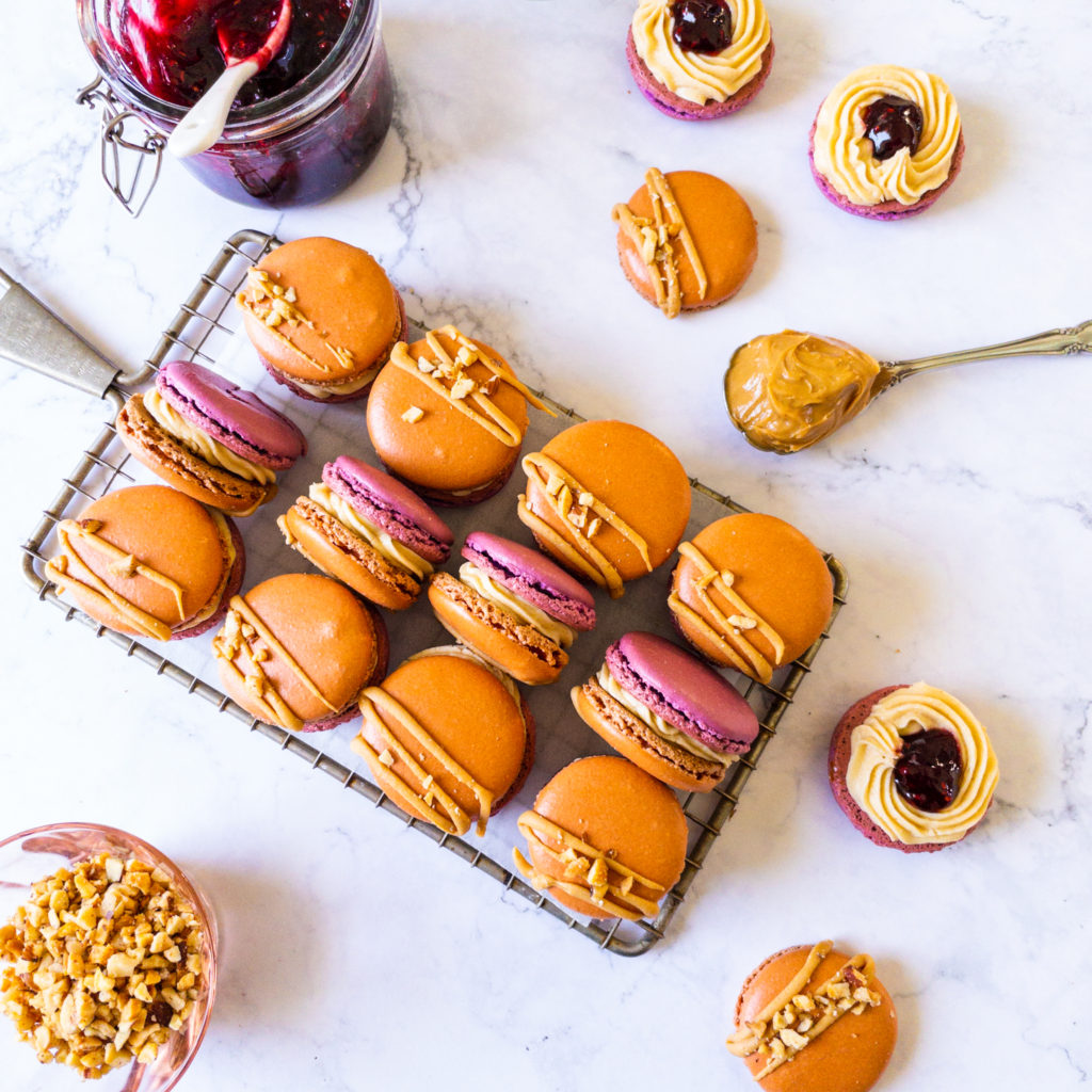 peanut butter jelly macarons on a tray with jelly and peanut butter on the side