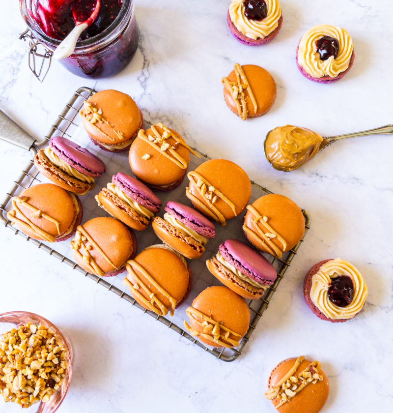 peanut butter jelly macarons on a tray with jelly and peanut butter on the side