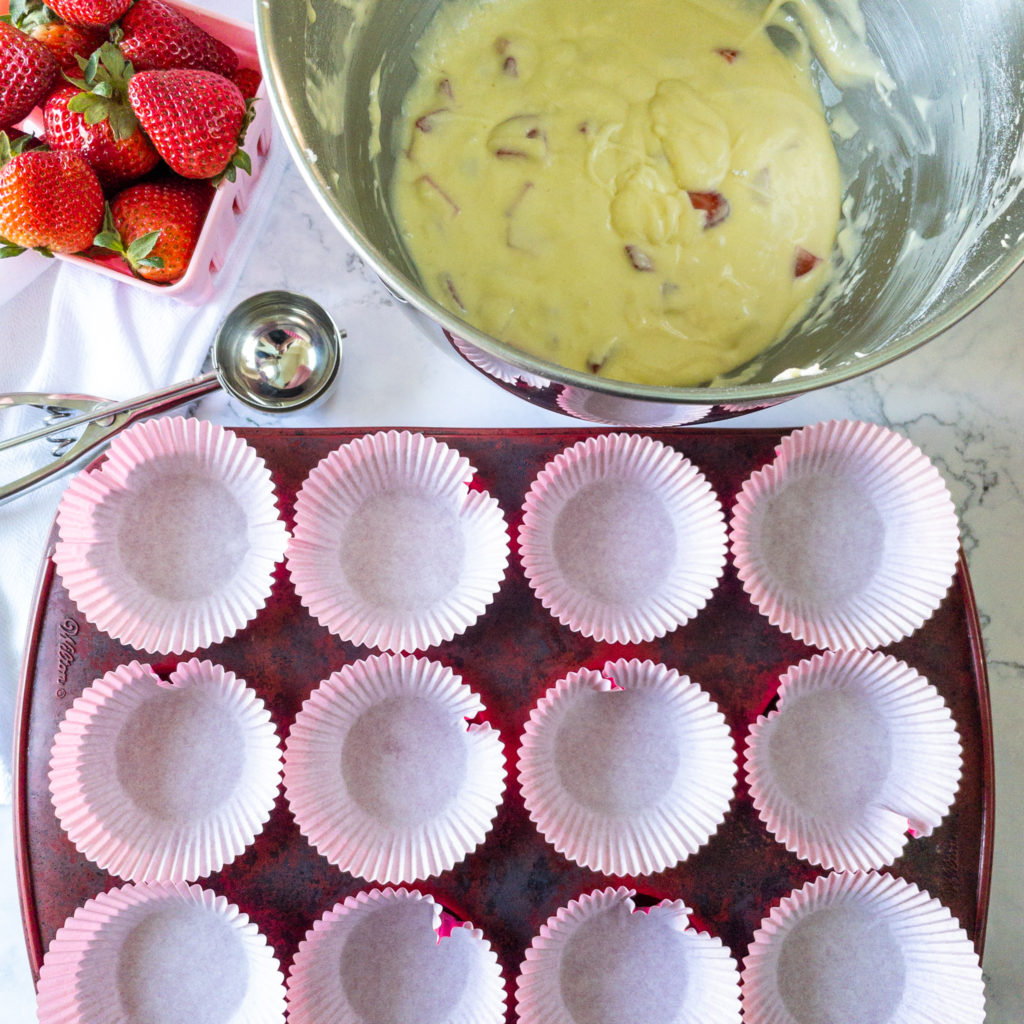 strawberry cupcake batter in bowl with lined muffin pan in front